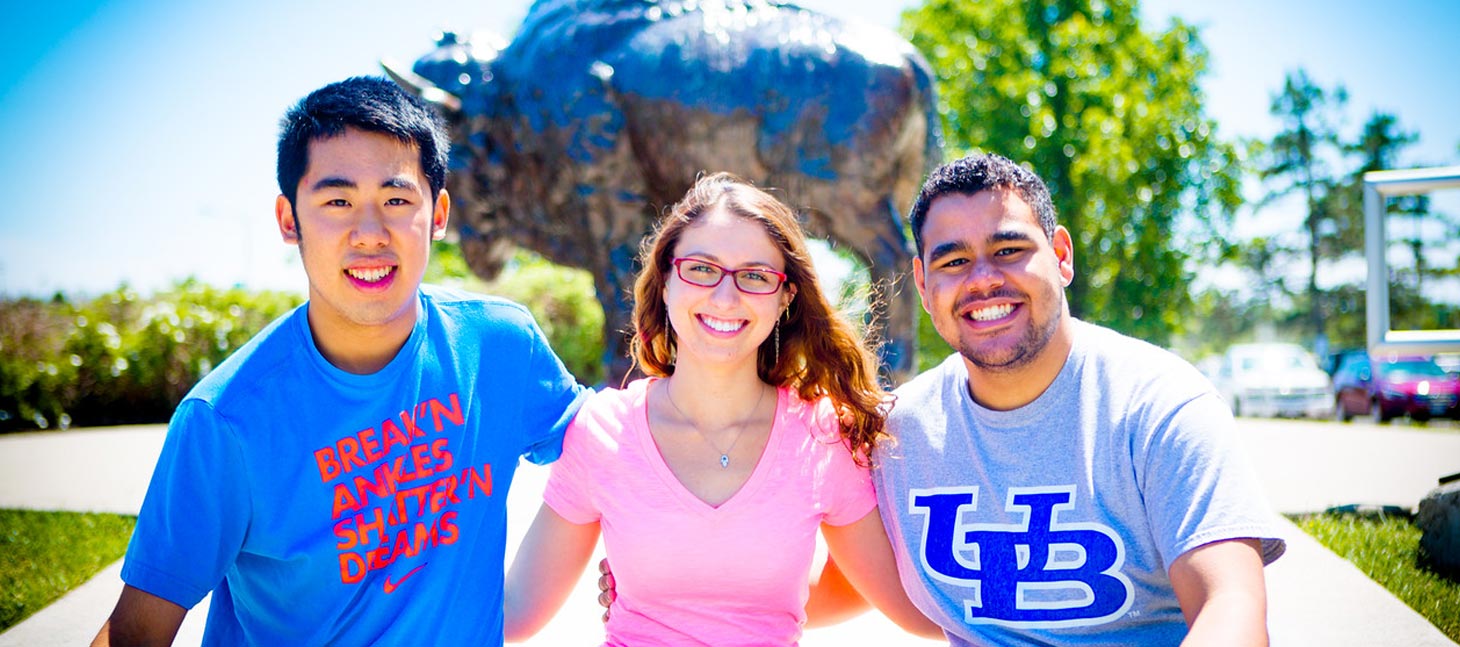 Students posing in front of a buffalo statue on campus